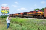 Three KCS engines rumble past a railfan and some billboards 